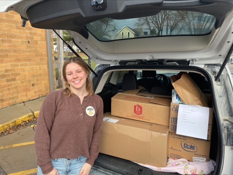 woman standing in back of car with boxes of food