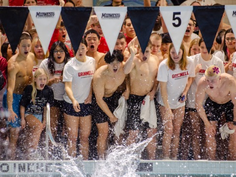 A group of students standing at the edge of a pool and cheering