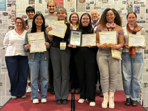 Ten people smiling and holding gold-edged paper certificates