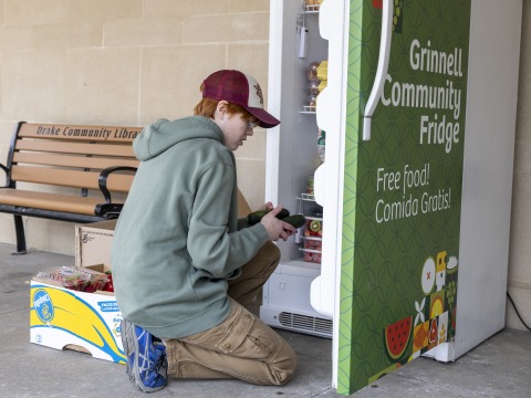 Person in hat stocking the community fridge