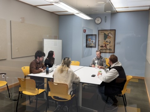 5 people sitting around a table discussing