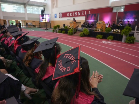 Graduates in the Field House seated in front of the commencement stage.