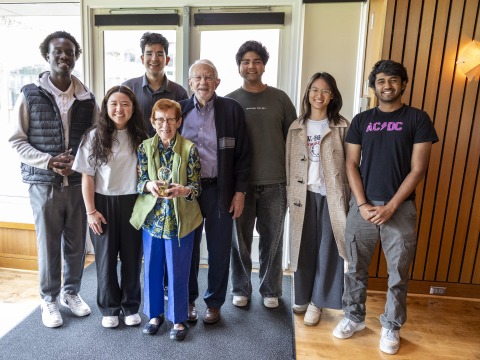 students standing with an older couple with an award 
