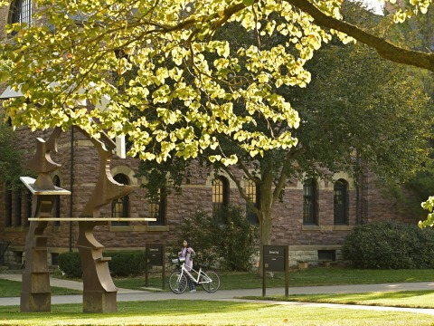 A girl walking a bicycle next to Steiner Hall