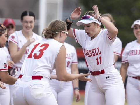 Two softball players high five while getting pumped up for the start of the game.
