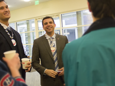 Jacob Wood and William McNulty wear their Grinnell Prize medals while talking to a small group of people