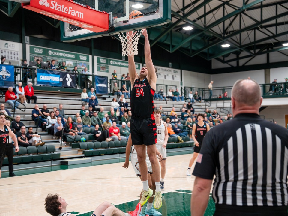 Grinnell basketball player in black hangs on the rim