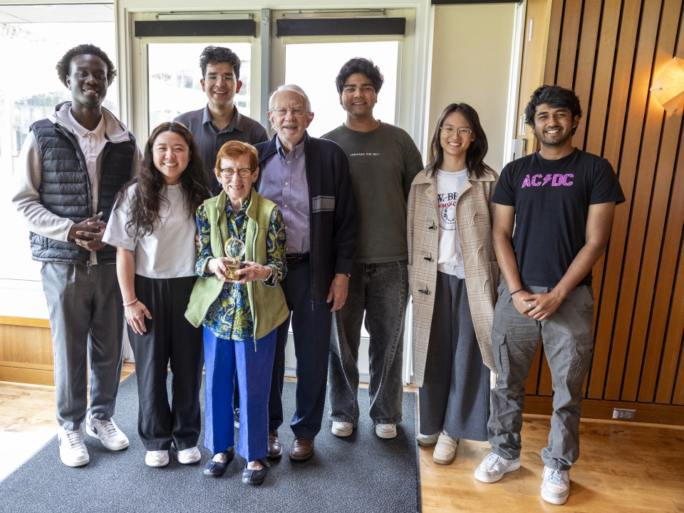 students standing with an older couple with an award 