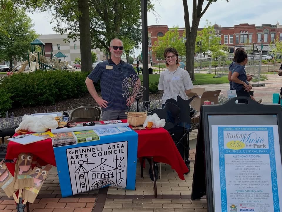 2 people standing behind a table outside 