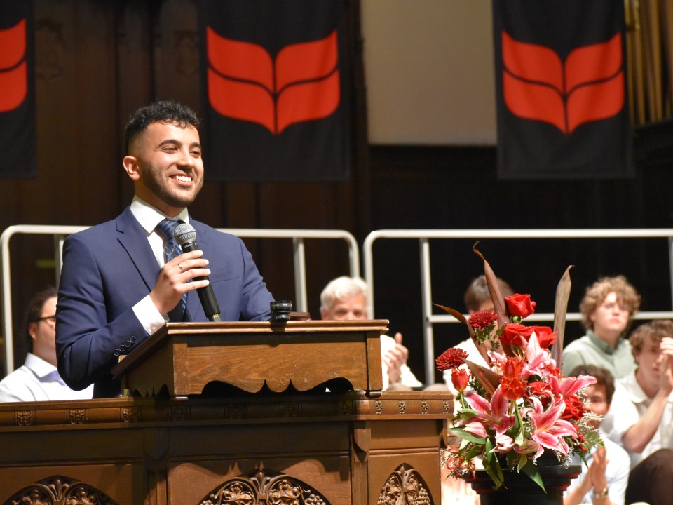 Grinnell College alum Nick El Hajj speaks at the podium for at the 2024 baccalaureate ceremony.