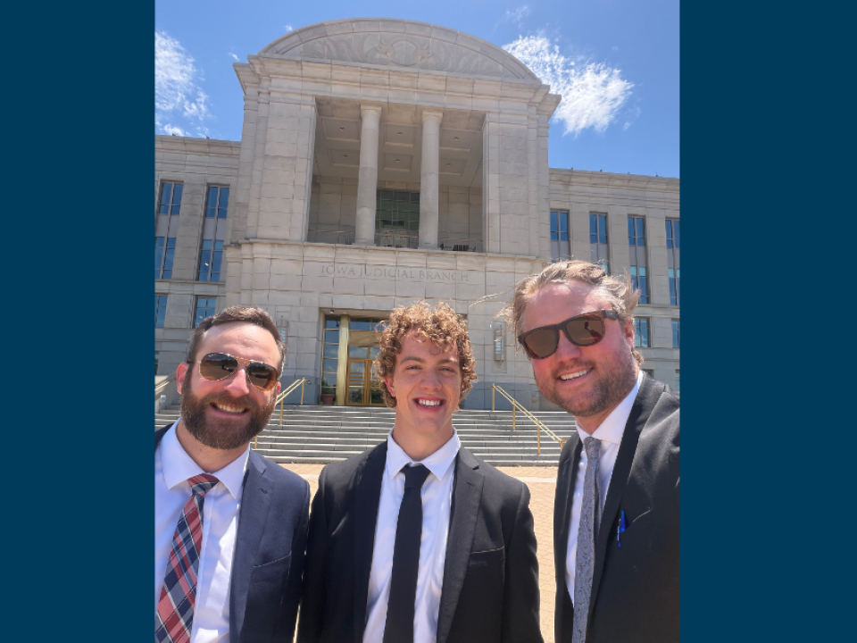 three people in front of building with blue sky 