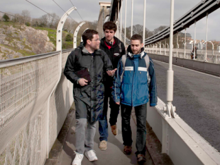 Three students on bridge walkway