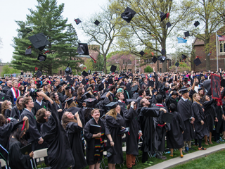 A crowd of graduates throw their caps into the air.