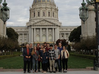 group of Grinnellians standing at a tall cast iron gate with a domed stone building behind them