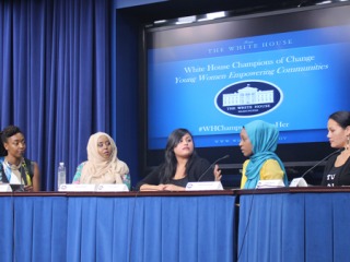Yesenia Ayala sits at a table with five other women in front of a screen reading White House Champions of Change Young Women Empowering Communities.