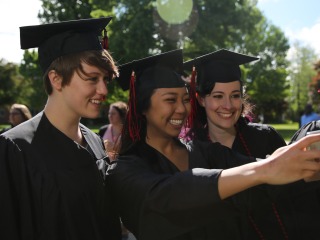 Three graduates in robes taking a selfie before the ceremony