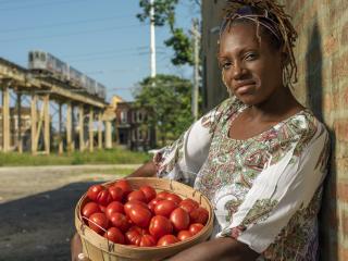 LaDonna Redmond in urban neighborhood carrying basket of tomatoes