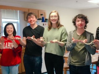 Students holding a long noodle stretched across their hands