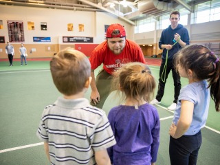 Coaching student talks to three young athletes