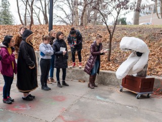 Students and Professor Lee Running critique a sculpture in an outdoor space