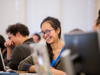 Student sitting at a computer in class laughs