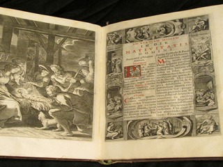 A large book opened to an engraving of the nativity