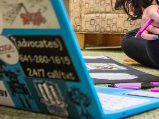 Close-up of a student sitting on the floor with an open laptop