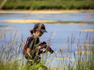 Student observing grass with large camera at the ready