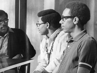 Thomas, right, is joined by Booker Carter ’71, Ernest Weston ’71, and Gregory Coggs ’70 at a 1969 campus meeting