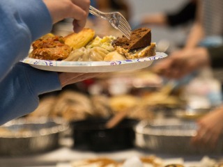 plate full of food held over tables laden with dishes