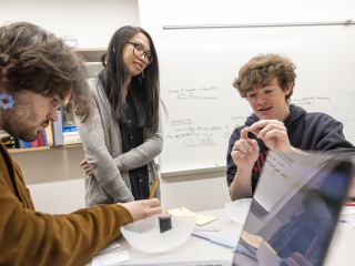 A faculty member and two students examine artifacts from an archaeological dig.