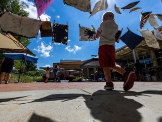 kid outside with paintings 