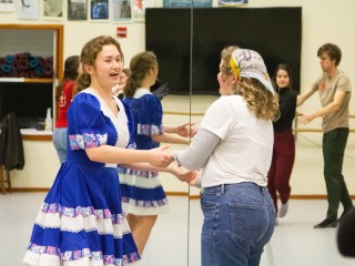 Blue-dressed student dancing with a student in a white shirt; two people dance behind them.