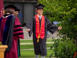 student walking across the commencement stage 