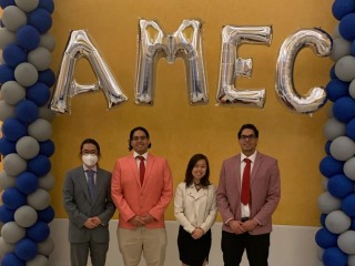 Four students with the AMEC balloon arch at the conference entrance.