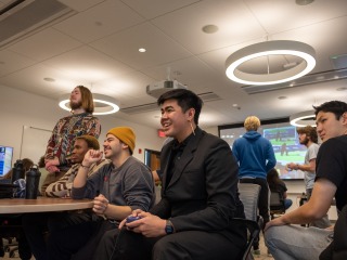 Prommolmard and other students hold controllers in a classroom, playing video games.