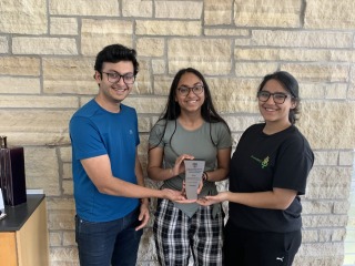 Three Grinnellians hold a trophy highlighting their case study win.