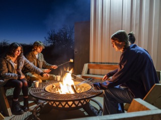 3 people roasting marshmallows over fire 