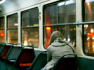 A woman looks out the window of a city bus