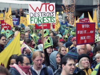 A crowd of protesters holding signs against the World Trade Organization