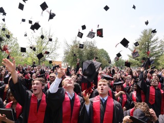 students throwing graduation hats in air 