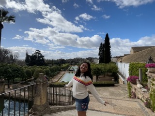 Maria Rossi smiles excitedly near a bridge. Calm waters pass by underneath.