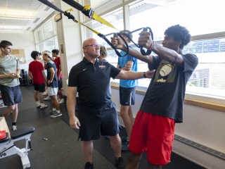 A coach works with athletes in the weight room