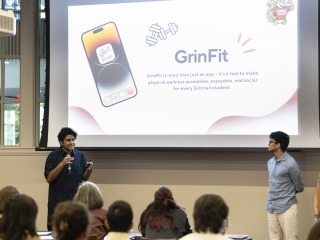 2 students presenting in front of people with a screen that says GrinFit