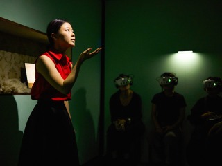 A young woman actress interacts with audience members wearing virtual reality headsets