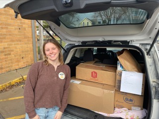 woman standing in back of car with boxes of food