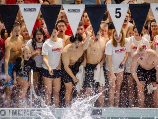 A group of students standing at the edge of a pool and cheering