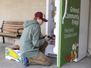 Person in hat stocking the community fridge