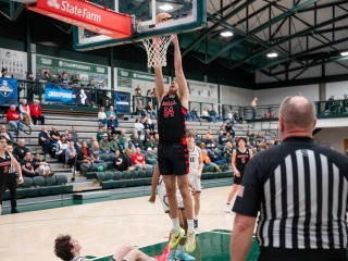 Grinnell basketball player in black hangs on the rim