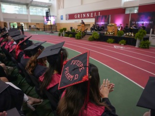 Graduates in the Field House seated in front of the commencement stage.